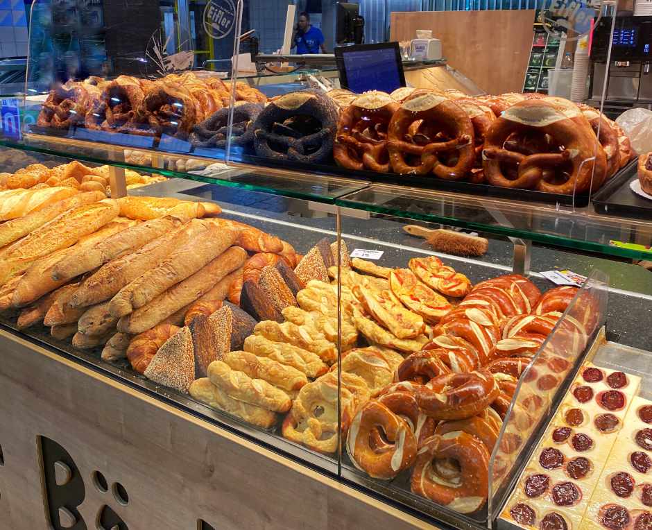 A bakery display with pretzels and baguettes at Der Bäcker Eifler