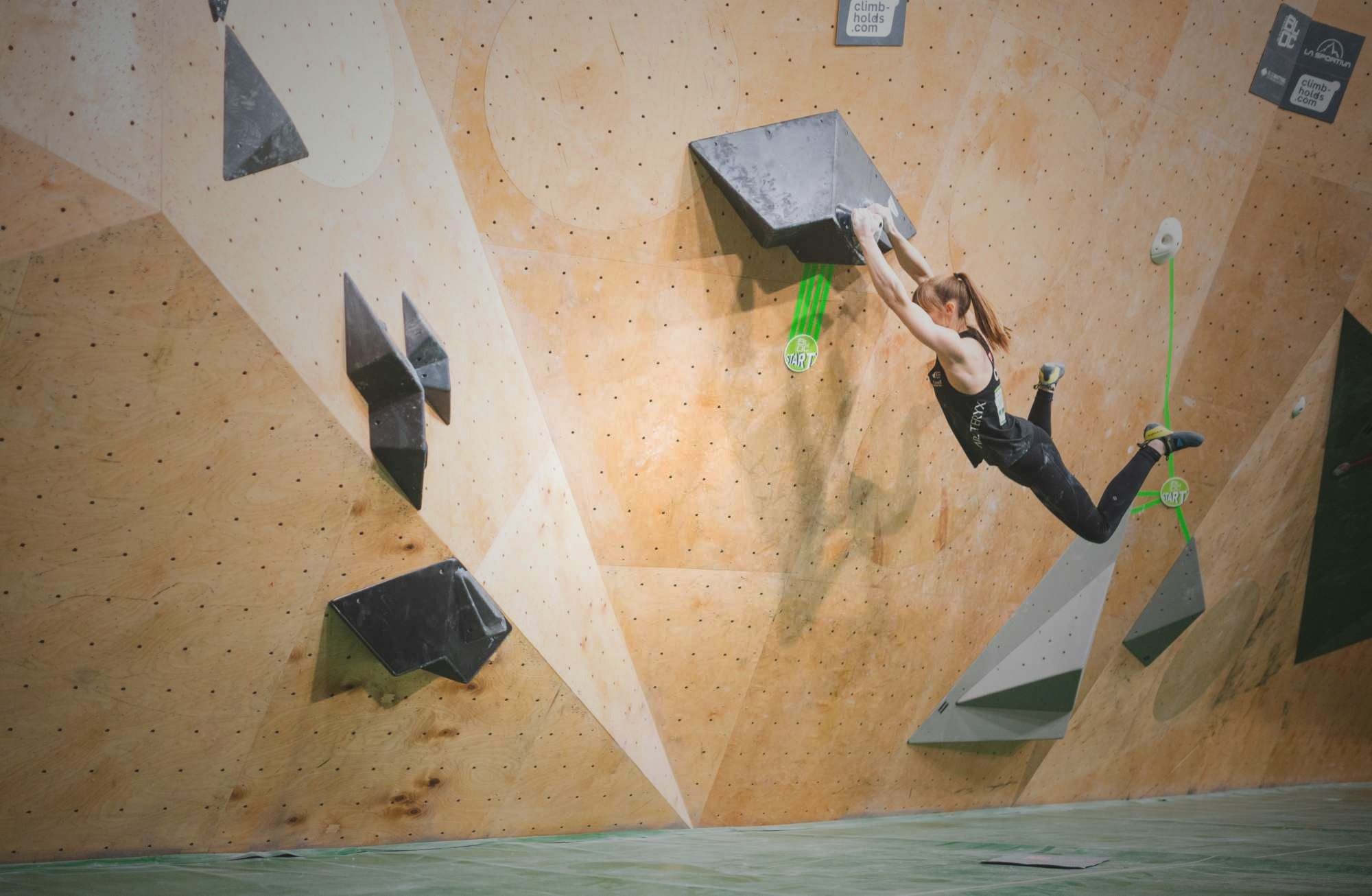 A climber swinging on a start hold in a competition